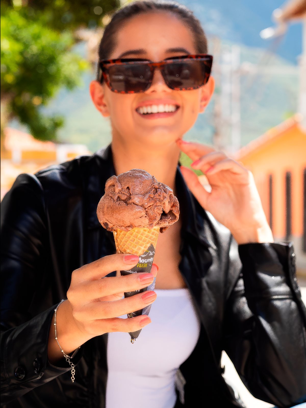 Clienta con lentes de sol y barquilla de chocolate frente al local